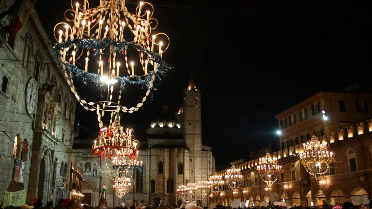 Piazza del Popolo ad Ascoli di notte durante il Carnevale, con i grandi lampadari accesi sopra la piazza